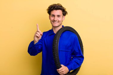 Genç yakışıklı adam gururla gülümsüyor ve kendinden emin bir numara oluyor. motor mekaniği kavramı
