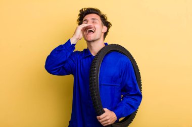 Genç yakışıklı adam kendini mutlu hissediyor, elleri ağzının kenarında bağırıyor. motor mekaniği kavramı