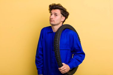 Genç yakışıklı adam omuz silkiyor, kafası karışık ve kararsız hissediyor. motor mekaniği kavramı