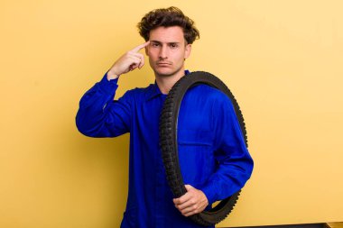 Genç yakışıklı, kafası karışık ve şaşkın hissediyor, sana deli olduğunu gösteriyor. motor mekaniği kavramı