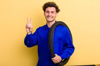 Genç yakışıklı adam gülümsüyor ve arkadaş canlısı görünüyor, iki numarayı gösteriyor. motor mekaniği kavramı