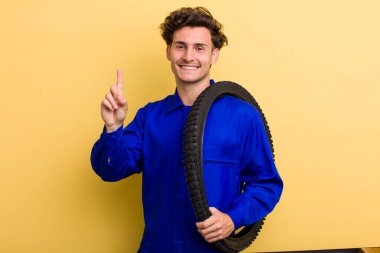 Genç yakışıklı adam gülümsüyor ve arkadaş canlısı görünüyor, bir numarayı gösteriyor. motor mekaniği kavramı