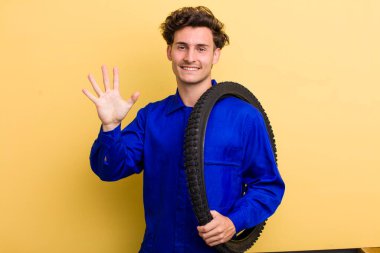 Genç yakışıklı adam gülümsüyor ve arkadaş canlısı görünüyor, beş numarayı gösteriyor. motor mekaniği kavramı