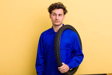 Genç yakışıklı adam üzgün, üzgün ya da kızgın hissediyor ve yana bakıyor. motor mekaniği kavramı