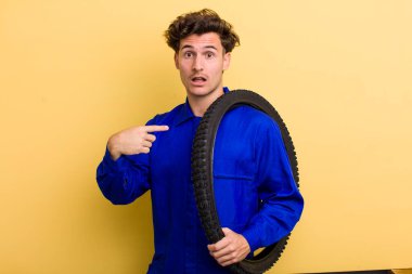 Şok olmuş ve ağzı açık, kendini işaret eden genç ve yakışıklı bir adam. motor mekaniği kavramı