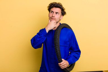 Genç yakışıklı adam düşünüyor, kuşkulu ve şaşkın hissediyor. motor mekaniği kavramı