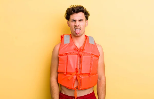若いハンサムな男はうんざりしていらいらして舌を出す ライフジャケットとボートのコンセプト — ストック写真