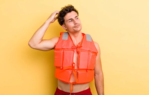 楽しそうに笑ったり空想したり疑ったりする若いハンサムな男 ライフジャケットとボートのコンセプト — ストック写真