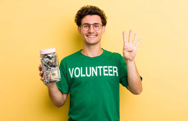 若いハンサムな男は笑顔で友好的に見える4番目を示しています 寄付とボランティアのコンセプト — ストック写真