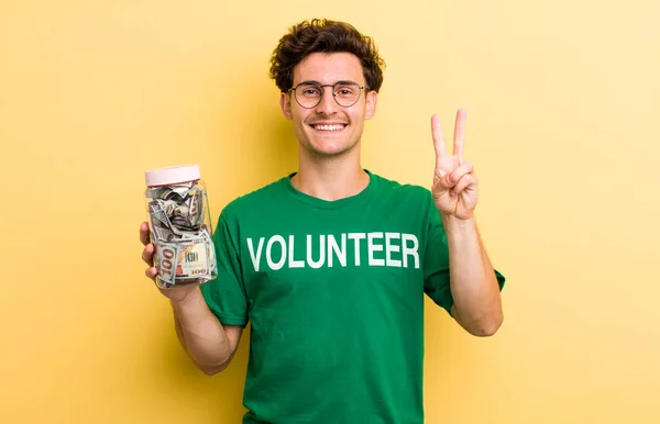 若いハンサムな男は笑顔で友好的に見える2番目を示しています 寄付とボランティアのコンセプト — ストック写真