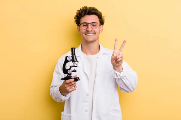young handsome guy smiling and looking happy, gesturing victory or peace. science student concept