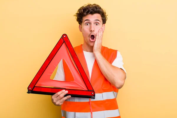 young handsome guy feeling shocked and scared. car emergency triangle concept