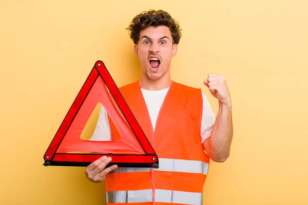 怒りの表情で積極的に叫んでいる若いハンサムな男 車緊急三角形のコンセプト — ストック写真