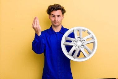 young handsome teenager making capice or money gesture, telling you to pay. car mechanic concept