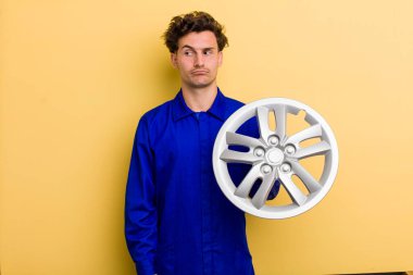 young handsome teenager feeling sad, upset or angry and looking to the side. car mechanic concept