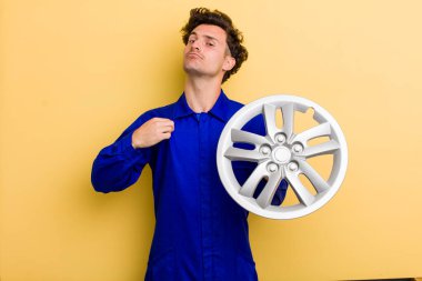 young handsome teenager looking arrogant, successful, positive and proud. car mechanic concept