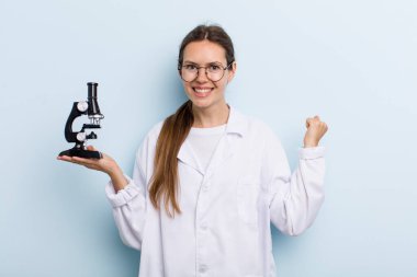 Genç bir kadın şokta, gülüyor ve başarıyı kutluyor. Mikroskoplu bir bilim adamı