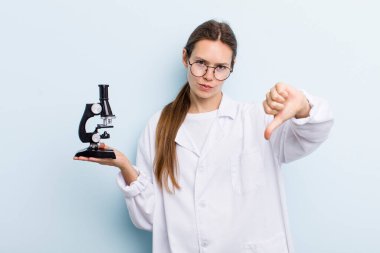 Genç yetişkin bir kadın kendini kötü hissediyor, baş parmağını kaldırıyor. Mikroskoplu bir bilim adamı