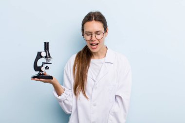 Genç yetişkin bir kadın agresif bir şekilde bağırıyor, çok kızgın görünüyor. Mikroskoplu bir bilim adamı