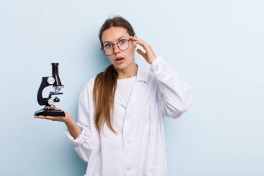 Genç yetişkin kadın şaşırmış görünüyor, yeni bir düşünce, fikir ya da konsept fark ediyor. Mikroskoplu bir bilim adamı