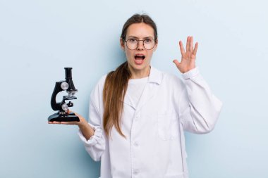 Elleri havada bağıran genç bir kadın. Mikroskoplu bir bilim adamı