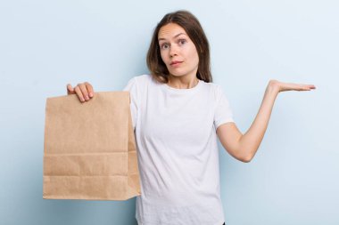 Genç bir kadın şaşkın, şaşkın ve şüpheci hissediyor. teslimat ve paket konsepti