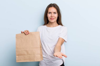 young adult woman smiling happily with friendly and  offering and showing a concept. delivery and take away concept