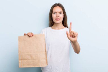 Genç yetişkin kadın gururla gülümsüyor ve kendinden emin bir numara oluyor. teslimat ve paket konsepti