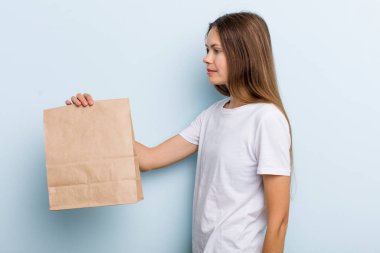 Profil görünümlü genç bir kadın hayal kuruyor, hayal kuruyor ya da hayal kuruyor. teslimat ve paket konsepti