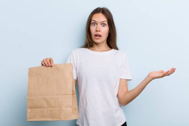 Genç bir kadın inanılmaz bir sürprizle şaşkın, şaşkın ve hayretler içinde kaldı. teslimat ve paket konsepti