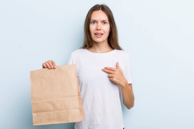 Şok olmuş ve ağzı açık, kendini işaret eden genç bir kadın. teslimat ve paket konsepti