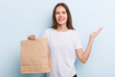 Genç yetişkin bir kadın kendini mutlu hisseder, bir çözüm ya da fikir bulduğunda şaşırır. teslimat ve paket konsepti