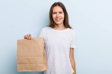 Genç yetişkin bir kadın mutlu ve hoş bir şekilde şaşırmış görünüyor. teslimat ve paket konsepti