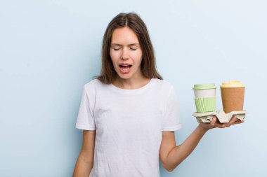 Genç yetişkin bir kadın agresif bir şekilde bağırıyor, çok kızgın görünüyor. kahve konseptini kaldır.