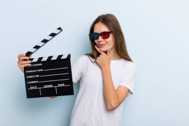 young adult woman smiling with a happy, confident expression with hand on chin. movie and cinema concept