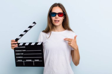 young adult woman looking shocked and surprised with mouth wide open, pointing to self. movie and cinema concept