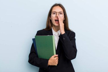 young adult woman feeling happy,giving a big shout out with hands next to mouth. university student concept