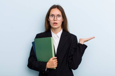 Genç bir kadın şaşırmış ve şok olmuş görünüyor. Çenesi düşmüş ve elinde bir nesne tutuyor. Üniversite öğrencisi konsepti