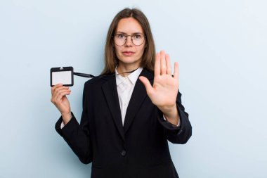 Genç bir kadın ciddi görünüyor. Avuç içini gösteriyor. Durdurma hareketi yapıyor. VIP geçiş kartı konsepti