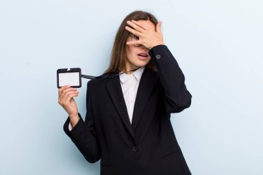 young adult woman looking shocked, scared or terrified, covering face with hand. vip pass id concept