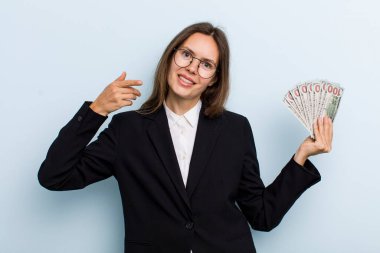 Genç, yetişkin bir kadın kendi gülüşünü işaret ederek kendine güvenerek gülümsüyor. Dolar banknotları konsepti