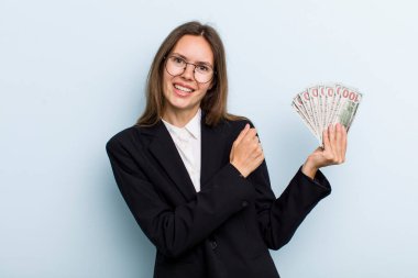 Genç yetişkin bir kadın kendini mutlu hissediyor ve bir meydan okumayla yüzleşiyor ya da kutluyor. Dolar banknotları konsepti