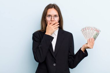 Genç, yetişkin bir kadın şok olmuş bir şekilde elleriyle ağzını kapatıyor. Dolar banknotları konsepti