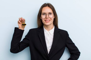 Genç yetişkin bir kadın mutlu bir şekilde gülümsüyor, eli kalçasında ve kendinden emin. Bitcoin konsepti