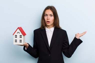 young adult woman looking surprised and shocked, with jaw dropped holding an object