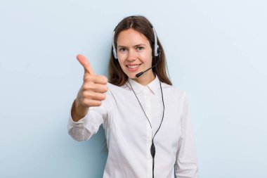 young adult woman feeling proud,smiling positively with thumbs up. telemarketer concept