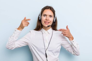 young adult woman smiling confidently pointing to own broad smile. telemarketer concept