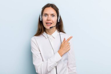 young adult woman looking excited and surprised pointing to the side. telemarketer concept