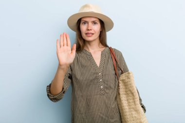 young adult woman looking serious showing open palm making stop gesture. summer concept