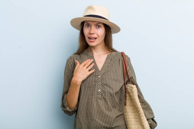 young adult woman looking shocked and surprised with mouth wide open, pointing to self. summer concept